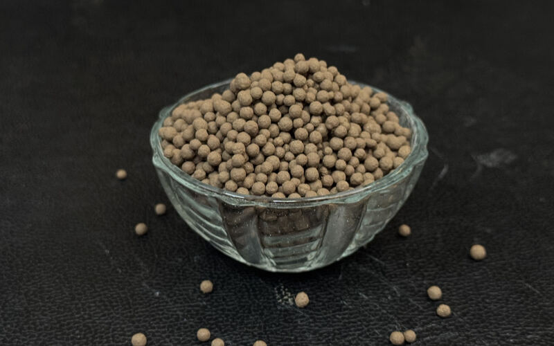 Natural brown bentonite soil conditioner granules in a glass bowl